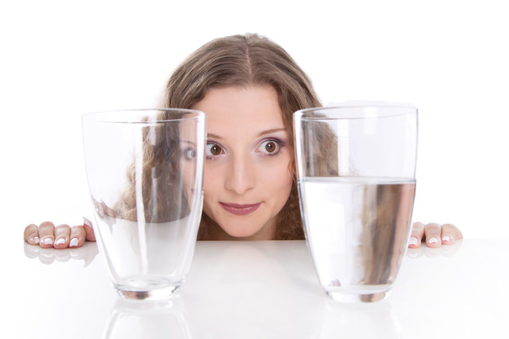 23796907 - half empty - half full. concept - all a matter of opinion. young woman with two glass of water, isolated on white